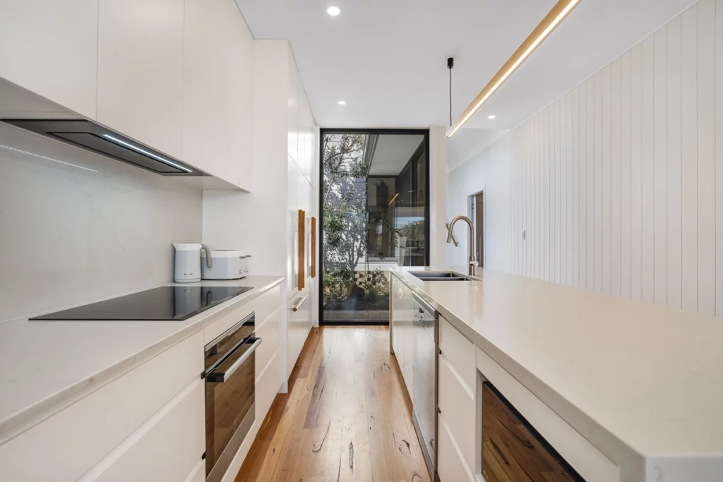 Sleek white kitchen with handleless cabinets and black-framed windows